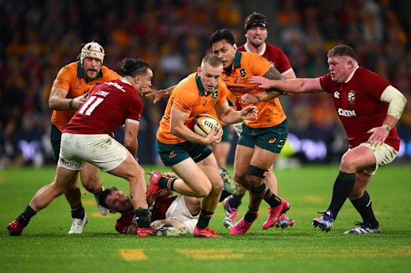 Max Jorgensen of the Wallabies runs with the ball, with Hugo Keenan on the ground.