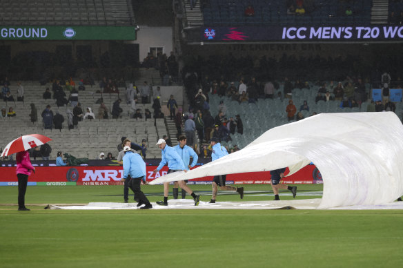 Ground staff place covers over the wicket.