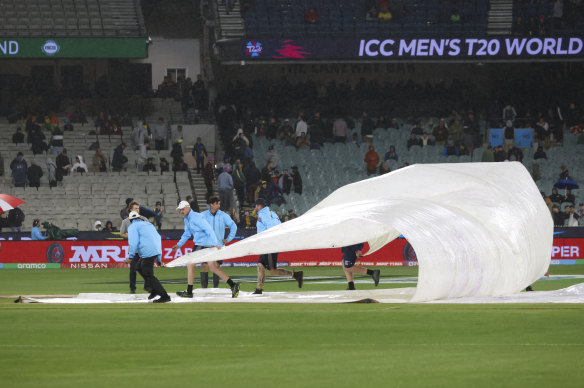 Ground staff place covers over the wicket.