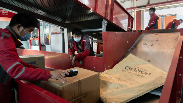 Employees wearing protective masks sort parcels at a JD.com Inc. delivery station in Beijing.