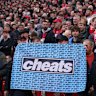 Liverpool fans hold up a flag that reads “Cheats”.