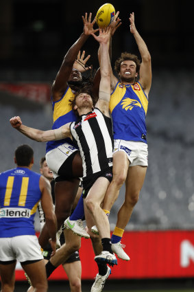 Nic Naitanui and Jack Petruccelle attempt to mark over Jordan Roughead of the Magpies.