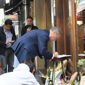 Federal Opposition Leader Bill Shorten writes in a card outside Pellegrini's cafe on Bourke Street, Melbourne.