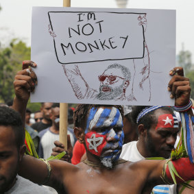 A Papuan students with faces painted with the colors of the separatist 'Morning Star' flag holds up a poster during a rally near the presidential palace in Jakarta.