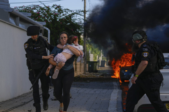 Police officers evacuate a woman and a child from a site hit by a rocket fired from the Gaza Strip, in Ashkelon.
