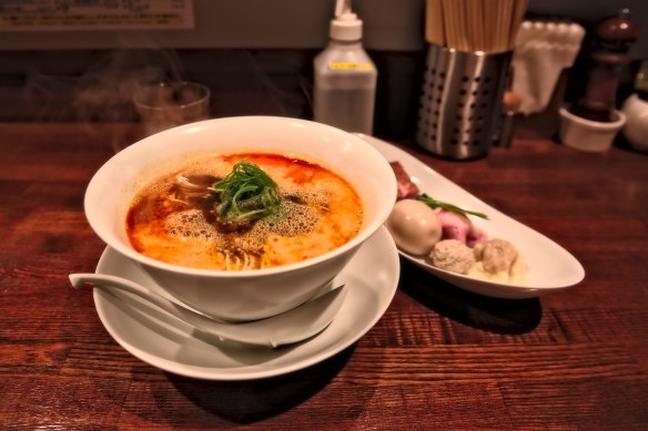 A bowl of spicy tantanmen noodles and some sides on the counter at Michelin-starred Nakiryu.