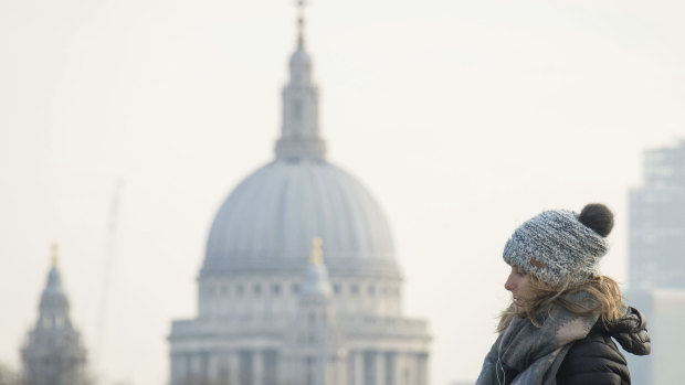 A woman wearing a winter coat, scarf and hat, backdropped by St Paul's Cathedral, crosses Waterloo Bridge, in central London, on Friday.  Freezing air from Russia is to grip the UK and will see temperatures plunge below zero from Sunday night..