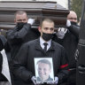 Workers carry the coffin and a portrait of Alexei Navalny out of the Church of the Icon of the Mother of God Soothe My Sorrows.