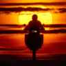 A man rides his bike over a hill as the sun rises in Frankfurt, Germany.