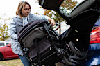 Woman loading pram into car boot