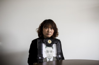 Lihong Wei holds a portrait of her husband, Xiaojun Chen, who was killed while working for a delivery company in Sydney.