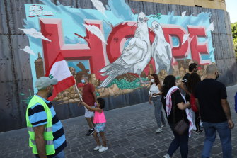 People walk past graffiti painted on the wall of a Beirut hotel damaged by the August 4 explosion. Lebanon remains mired in crisis.