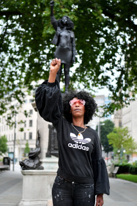 Black Lives Matter protestor Jen Reid poses for a photograph in front of a sculpture of herself.