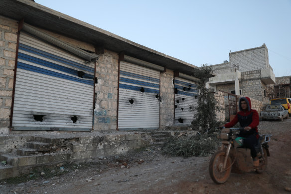 A man rides his motorcycle past damaged shops after an operation by the US military in the Syrian village of Atmeh in Idlib province on Thursday.