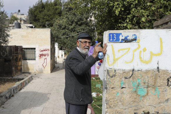 Mohammed El-Kurd’s father, Nabil, outside the family home in Sheikh Jarrah. On the wall beneath the street sign is written “we won’t leave”.