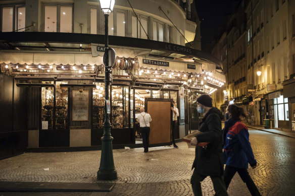 Waiters close a bar terrace in Paris. French restaurants, cinemas and theatres are trying to figure out how to survive a new curfew aimed at stemming the flow of record new coronavirus infections. 