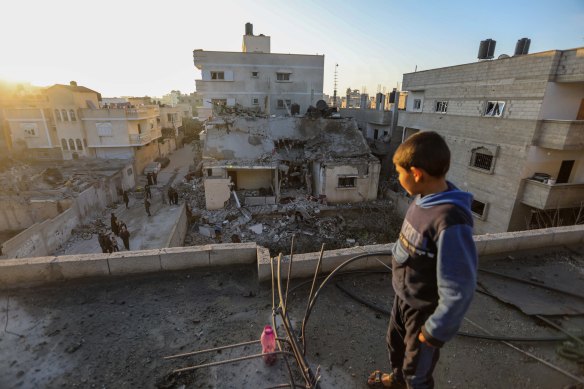A boy stands atop a damaged building as others inspect damage to their homes following Israeli air strikes on Rafah, 
