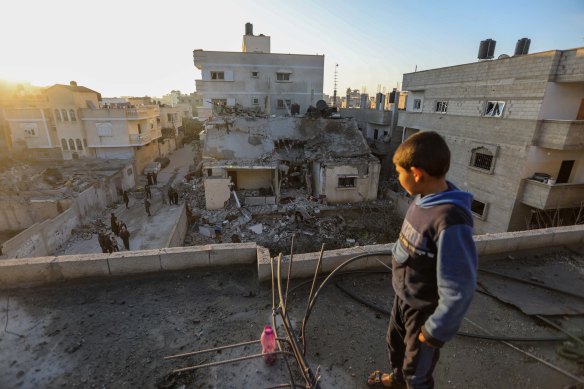 A boy stands on top of a destroyed building while others inspect the damage to their homes following Israeli air strikes on Rafah. 