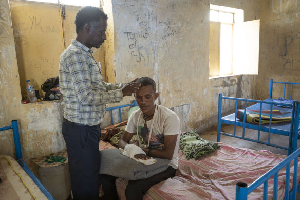 Surgeon and doctor-turned-refugee, Tewodros Tefera, checks the wounds of 22-year-old Abrahaley Minasbo.