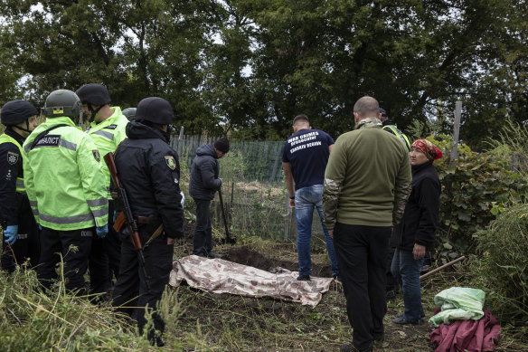 Ukrainian police investigators and the war crime prosecutor for the Kharkiv Oblast region work to recover the bodies of two men in the liberated village of Zaliznychne, Ukraine on September 11.