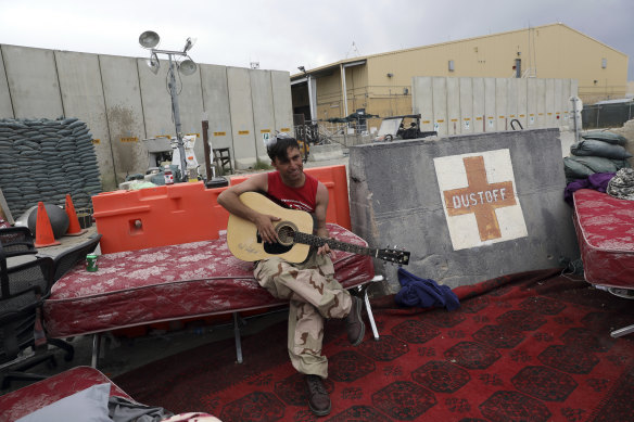 An Afghan soldier plays a guitar that was left behind after the American military departed Bagram air base. 