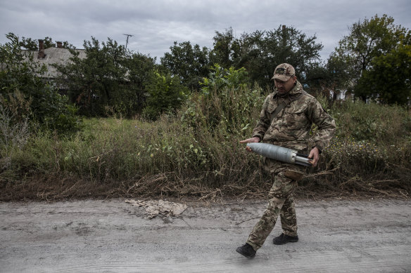 A Ukrainian soldier carries away a tank shell in the liberated village of Zaliznychne on September 11. 