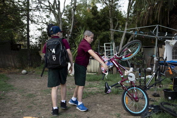Jordan and Joel play with a bike before school in the backyard.