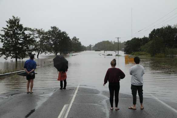 People look across a heavily flooded Manning River Drive outside Taree.