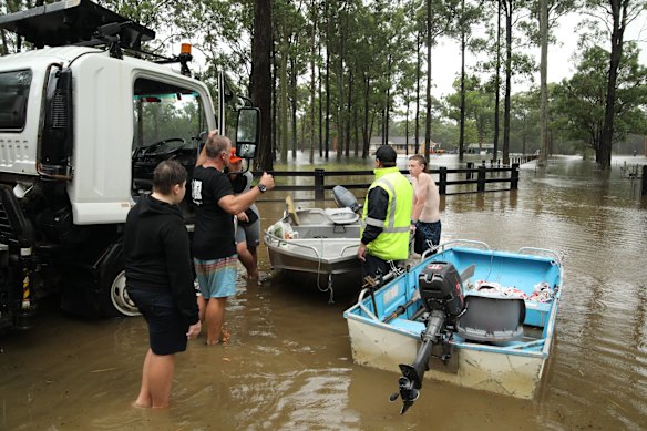 Lance Devaney and his son, Jackson, walk their boats back to their house in Old Bar, near Taree.