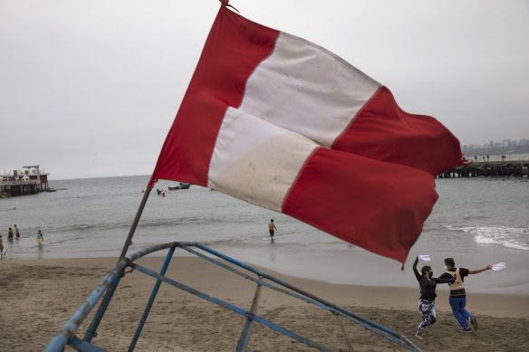 A Peruvian flag flies on the beach in Chorrillos, Lima, as a couple dances on the sand. More than 250 Chinese fishing vessels are operating just outside Peru's maritime zone.