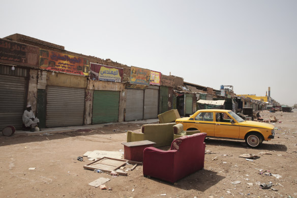 A man sits by shuttered shops in Khartoum. Street battles have locked people inside their homes and forced shops to close.