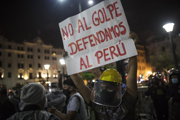 A protester holds a banner that reads in Spanish: "No to the coup, let's defend Peru," in favour of President Martin Vizcarra in Plaza San Martin in Lima.
