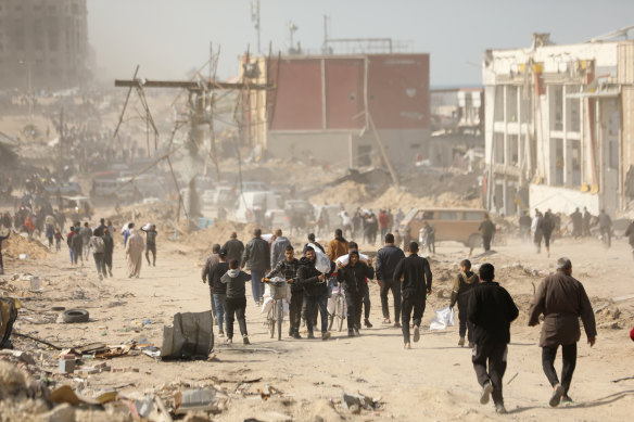 Palestinians carry bags of flour received from an aid truck that arrived in the west of Gaza City on March 6.