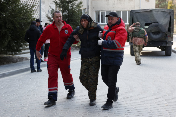 A patient is assisted by medical staff as he arrives at Novoiavorivsk District Hospital after a series of Russian missiles struck the International Centre for Peacekeeping and Security at the nearby Yavoriv military complex.