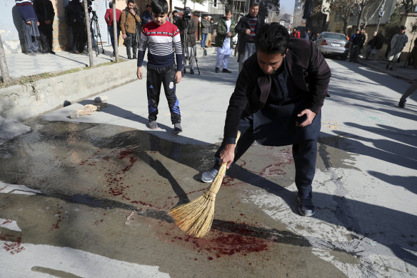 An Afghan man sweeps blood after gunmen fired on a car in northern Kabul on Sunday, killing two women judges who worked for Afghanistan's high court.