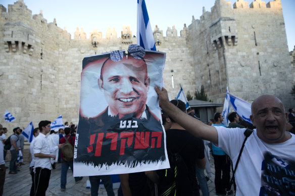 A marcher holds a aposter with a photo of new Israeli Prime Minister Naftali Bennett with the word “liar” in Hebrew, near the Damascus Gate on Tuesday.