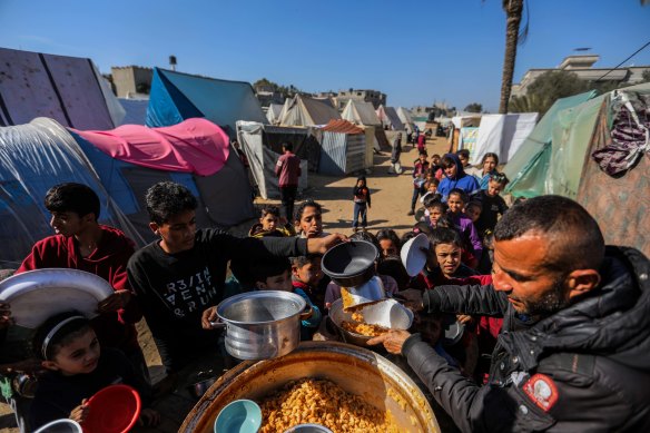Displaced people line up to receive food in a camp in Rafah, Gaza.