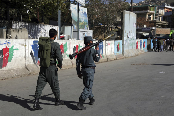 Afghan security personnel patrol with a rocket-propelled grenade launcher at the site of the Kabul University attack.