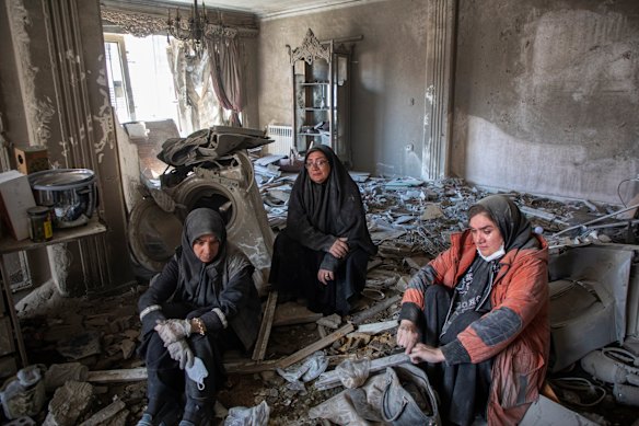 I residenti siedono tra le macerie di un edificio residenziale colpito da un attacco aereo il 30 marzo nella parte occidentale di Teheran.