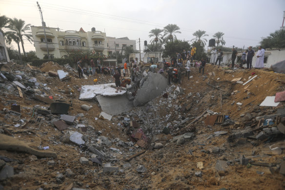 Palestinians inspect the damage of a destroyed house that was hit by an Israeli airstrike.