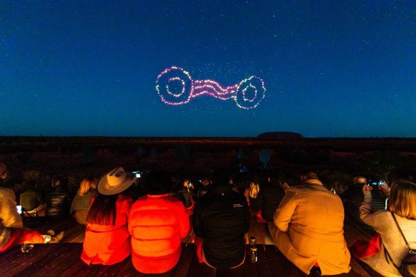 People watch Wintjiri Wiru light up the night sky above Uluru.