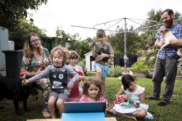 Hannah and Mark Tuton, with their children, learning to play the ukulele through an online lesson.