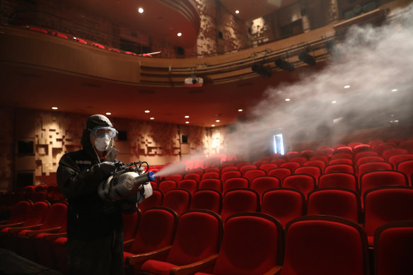 A disinfection worker wearing protective clothing sprays antiseptic solution in a theatre in Seoul. 