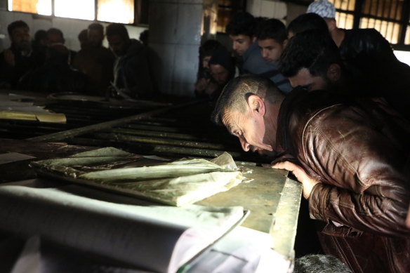 People peer into a chamber at Sednaya Prison.