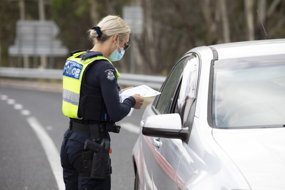 A Victoria Police officer checks for permits at a roadblock at Genoa, on the Victorian border, on Wednesday.