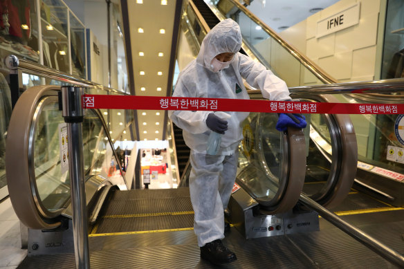 A worker sprays antiseptic solution on escalator handles at a department store in Seoul, South Korea.
