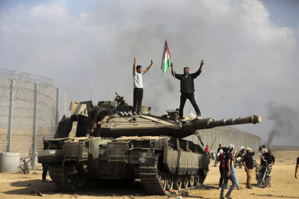 Palestinians celebrate with a destroyed Israeli tank at a break in the Gaza Strip fence on the weekend.