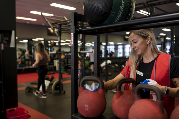 Bryony Alley-Kent sanitises gym equipment at a Fitness First at Bondi Junction.