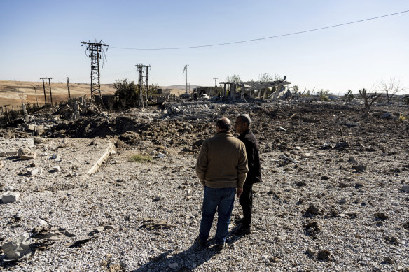 People look at a site damaged by Turkish airstrikes that hit an electricity station in the village of Taql Baql, in Hasakeh province, Syria.