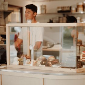 The front counter holds a cabinet of cakes. 